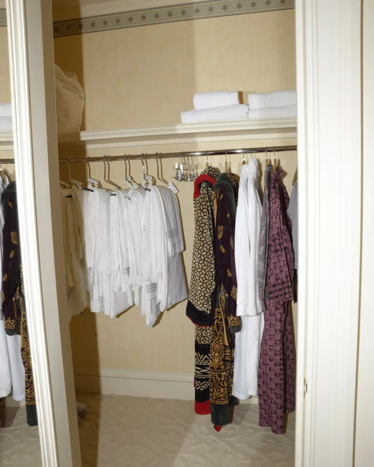 A neatly organized walk-in closet with hanging clothes beside a full-length mirror
