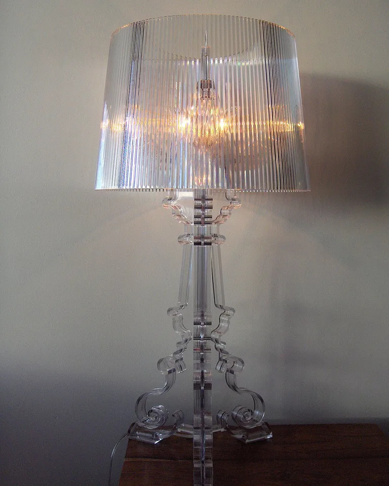 A bedside table with a lamp tucked beside a leaning full-length mirror
