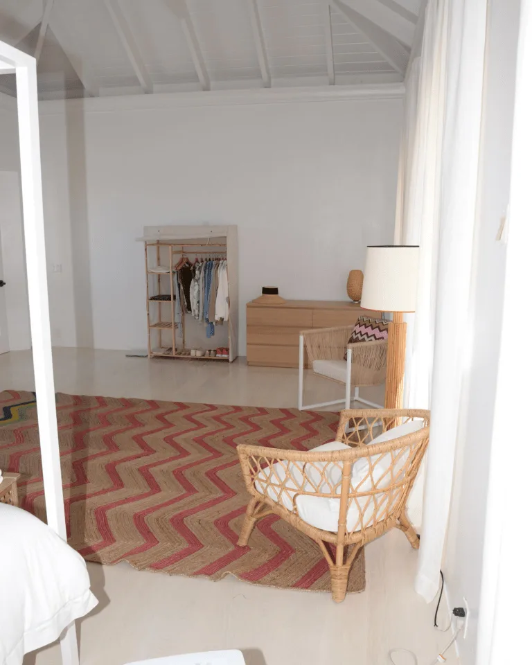 A cozy bedroom corner with a wicker chair, chevron rug, and styled mirror vignette