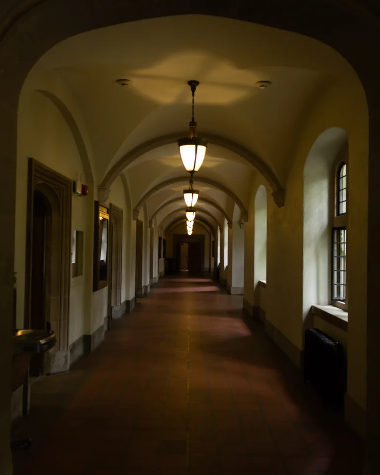 Hallway with a row of pendant lights leading toward a courtyard