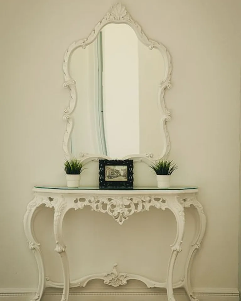 A narrow console table styled with decor beside a front door entry