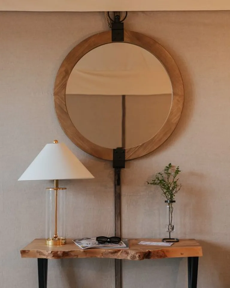 A round mirror hung on the wall above a styled console table