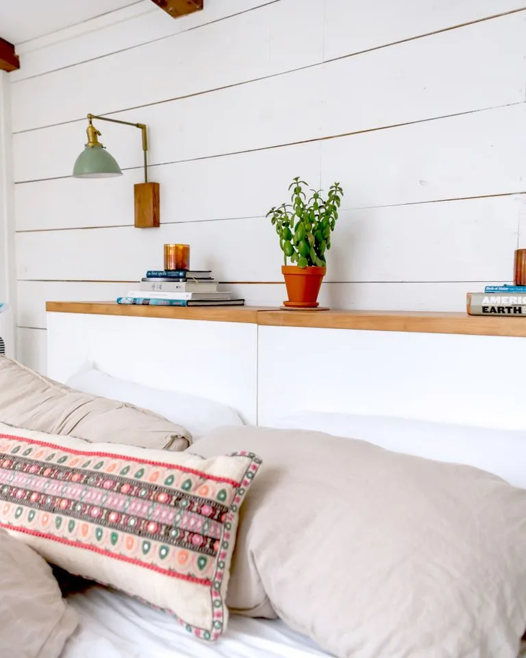White shiplap paneling installed on the wall behind a farmhouse bed