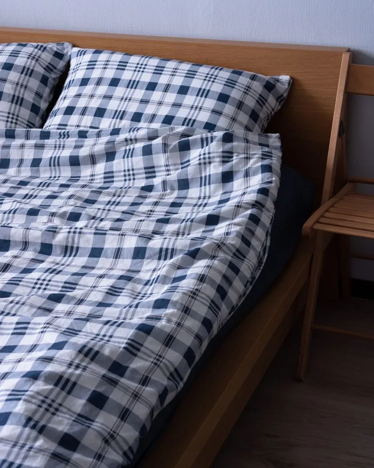 Bed made with a blue and white plaid duvet cover in farmhouse style