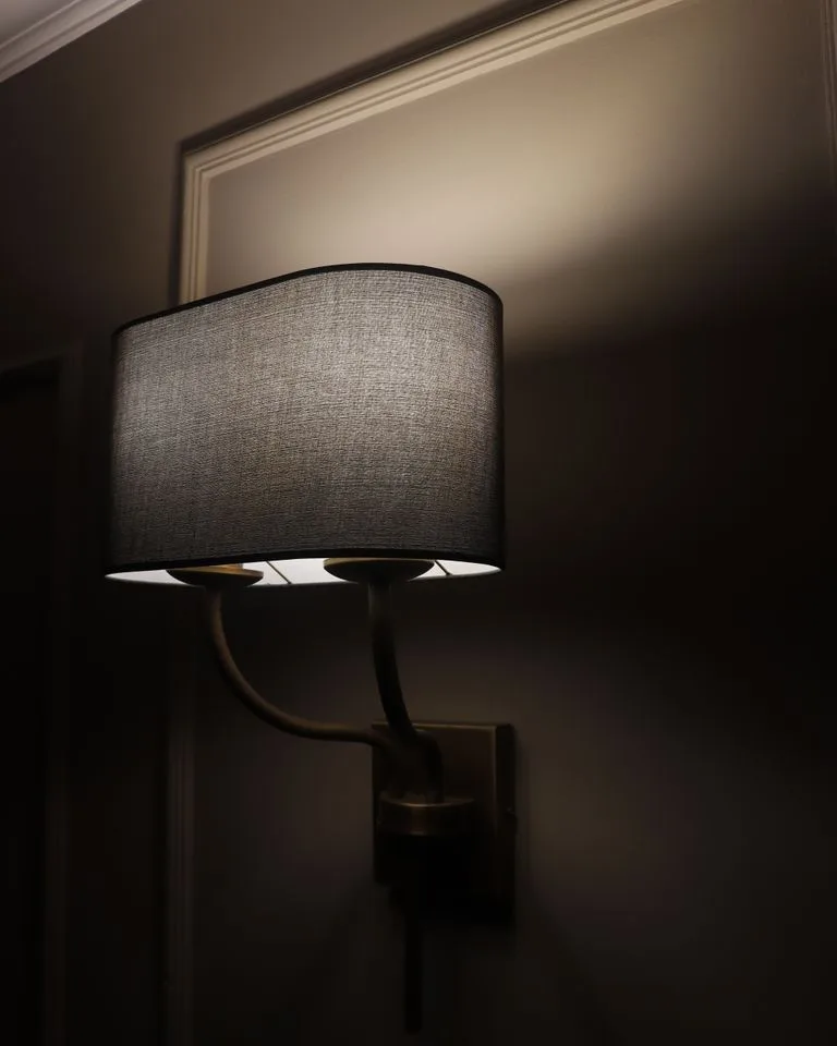 Black metal wall sconce mounted beside a bed for reading light