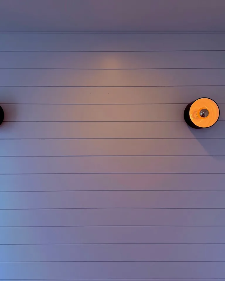Modern interior wall with two illuminated sconces on a paneled wall