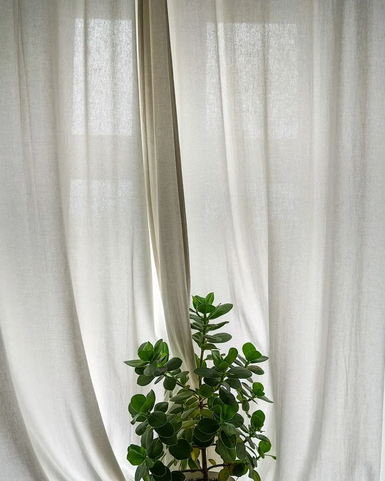 Natural linen curtains hung high and wide on a bedroom window