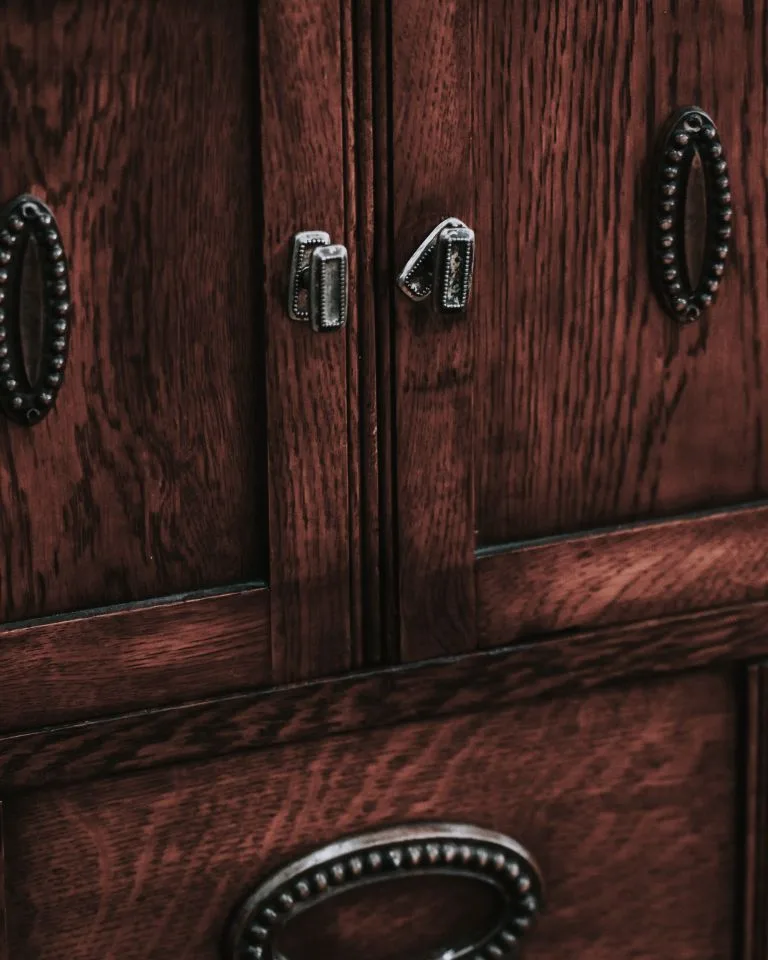 Close-up of vintage-style metal drawer pulls on a dark wood dresser