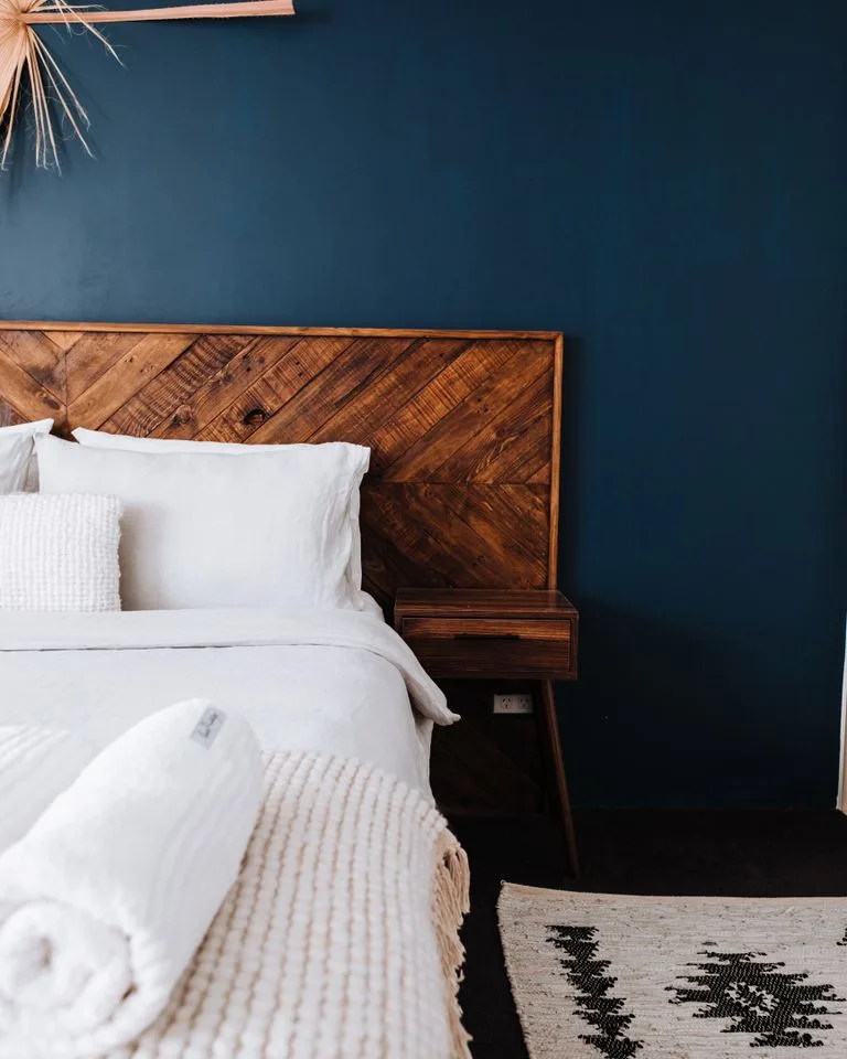 Bed with a reclaimed wood plank headboard in a farmhouse bedroom