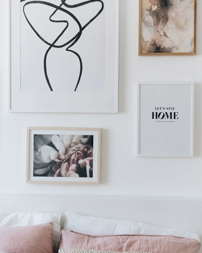 Gallery wall of mixed picture frames above a bedroom dresser