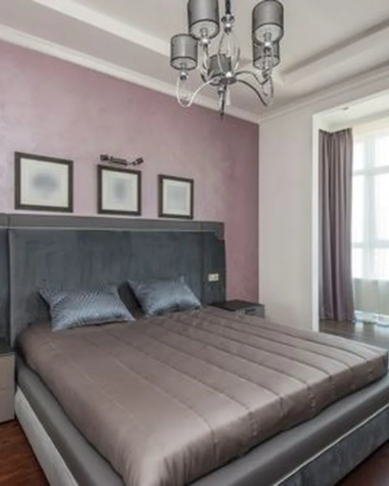 Bed positioned between two tall windows in a bright French-style bedroom