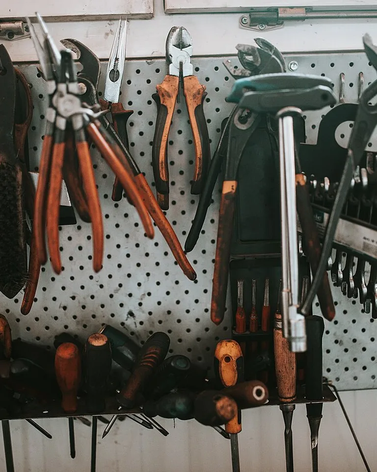 Pegboard panel on a wall with hooks holding bags and small items