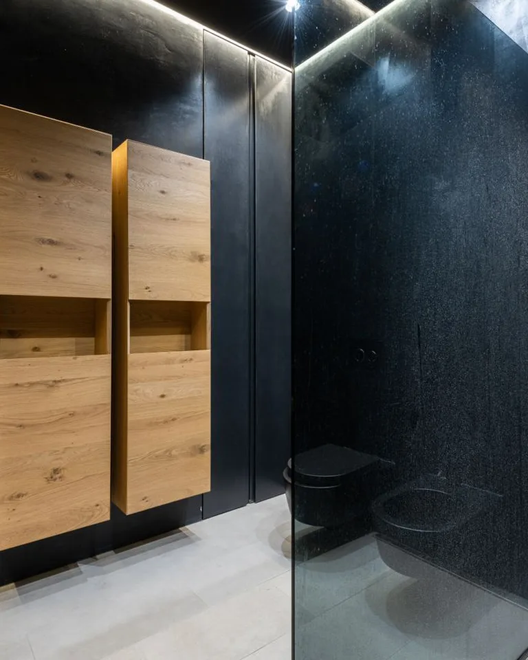 Moody half bathroom with dark walls, wood vanity, and soft overhead lighting