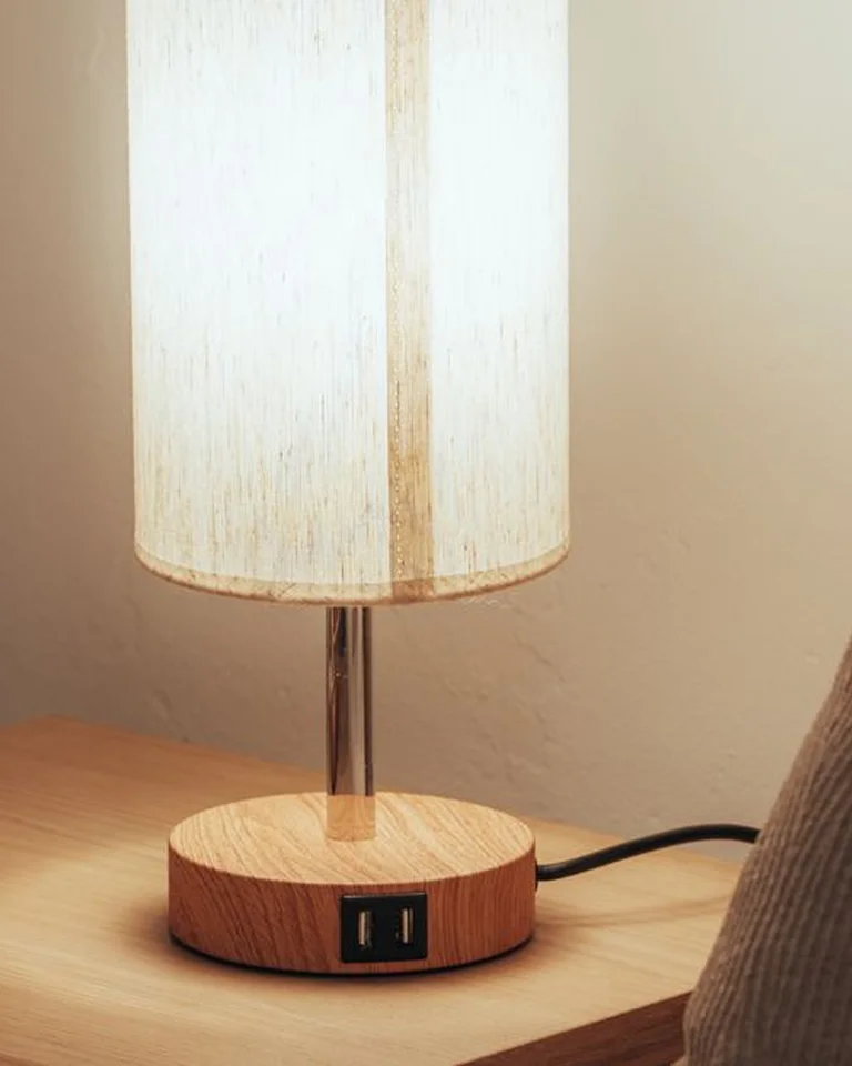 A warm bedside lamp glowing on a wooden nightstand