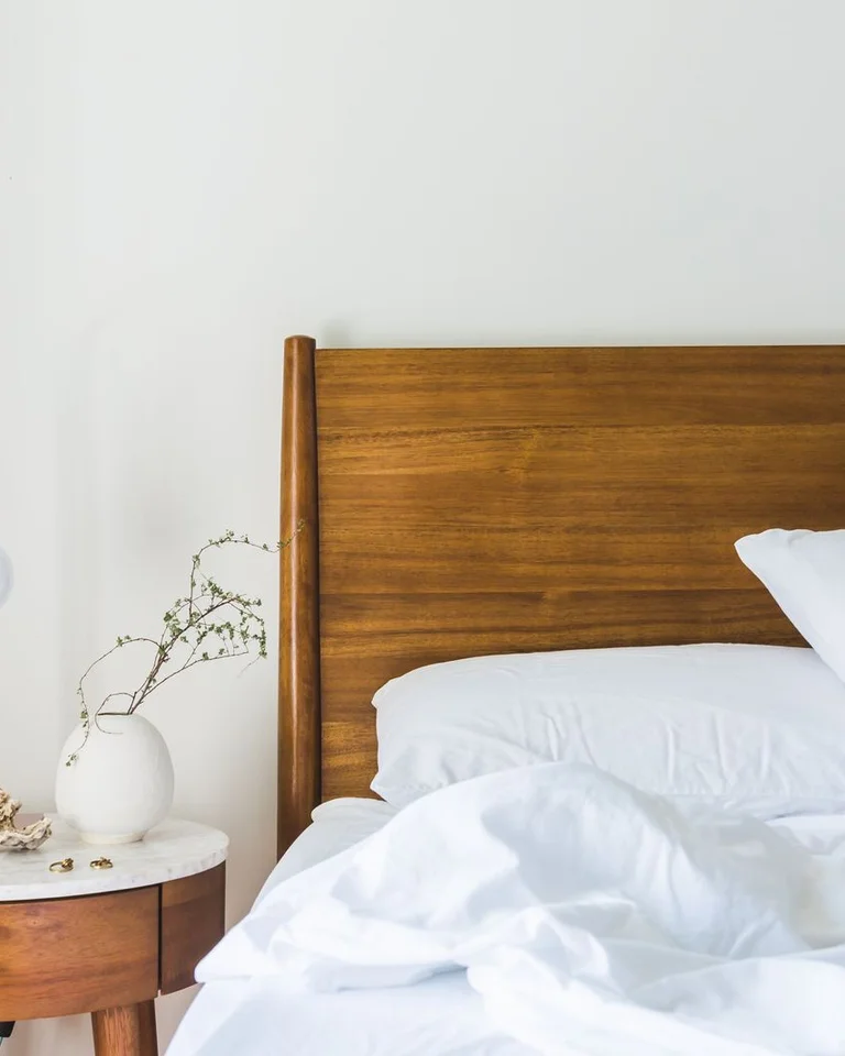 A bedroom with a wooden plank headboard and white bedding
