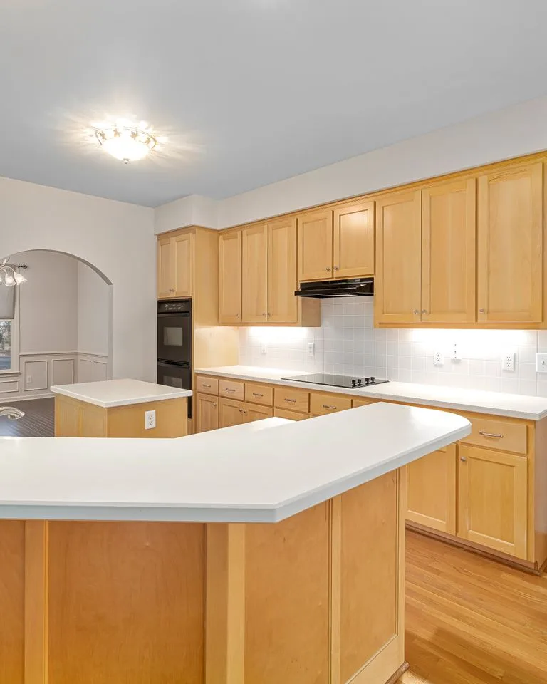 Pale natural wood kitchen cabinets with white counters