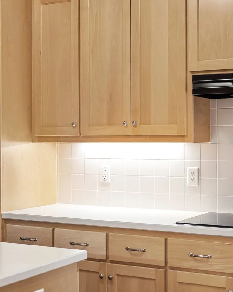 Light wood kitchen cabinets with dark bar handles and white tile