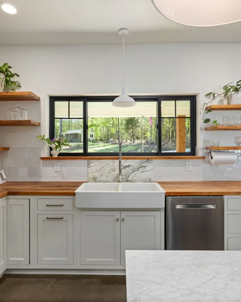 Open wooden shelves styled with plants and glassware in a kitchen