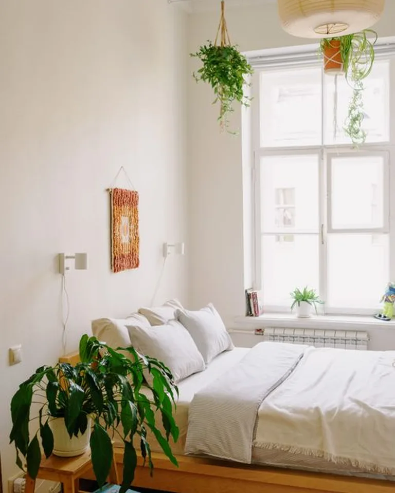 A finished no-closet bedroom at dusk with a styled rack, layered bedding, and warm lighting