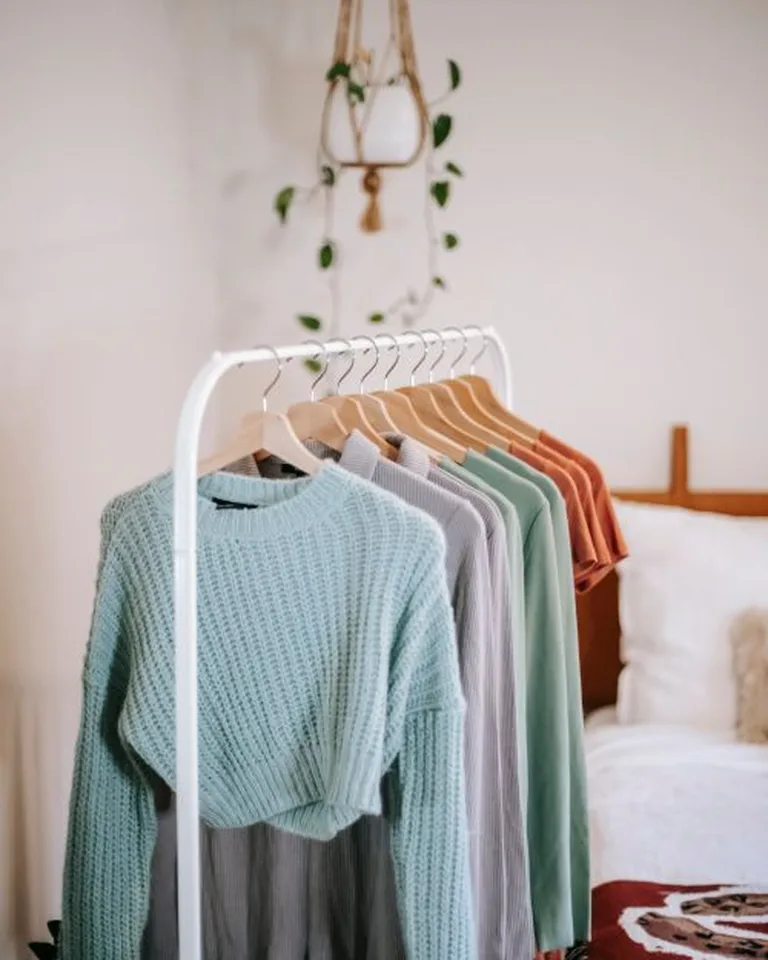 A curated open garment rack styled like a boutique display in a no-closet bedroom