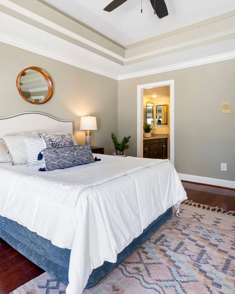 A large area rug anchoring the bed in a warm no-closet bedroom