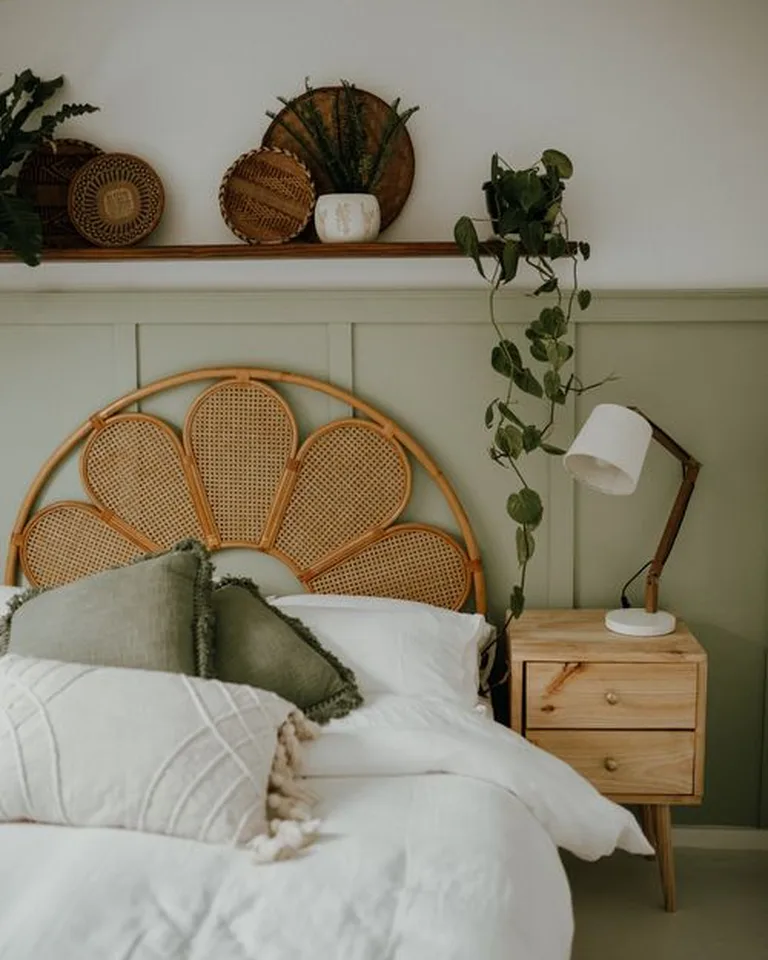 A bedroom with a slim rattan headboard leaned against the wall behind a neatly made bed