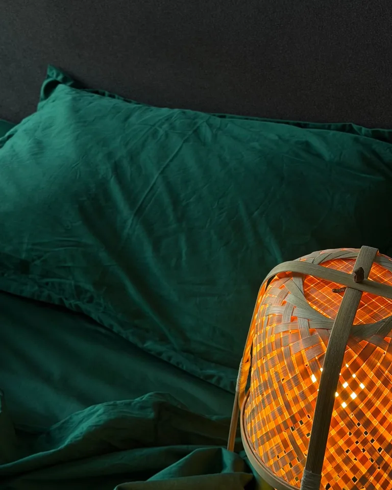 Deep green bedding with a glowing bedside lamp