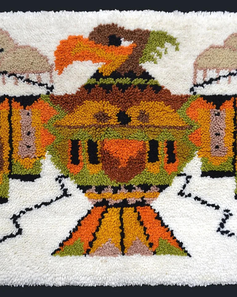 Vintage hooked rug with a thunderbird motif in green, orange, and brown on white