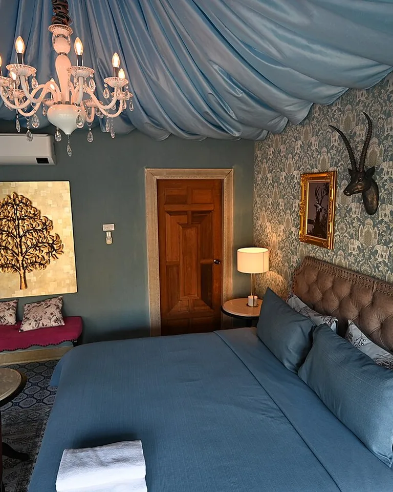 Bedroom with a tufted upholstered headboard, blue bedding, and a draped fabric ceiling