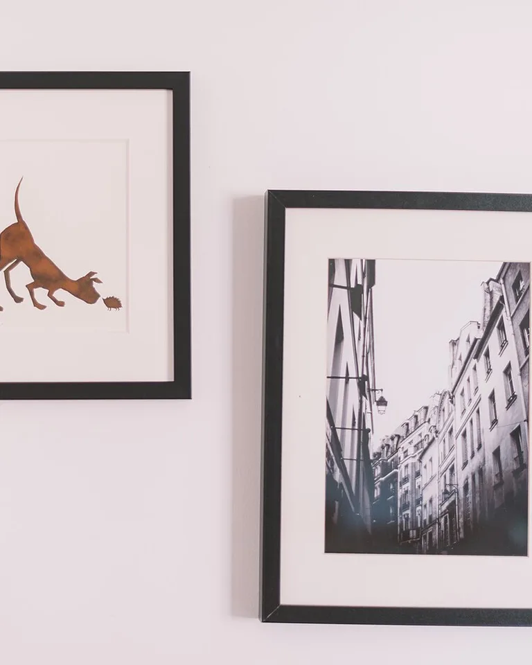 Two black-framed art prints hung on a white wall