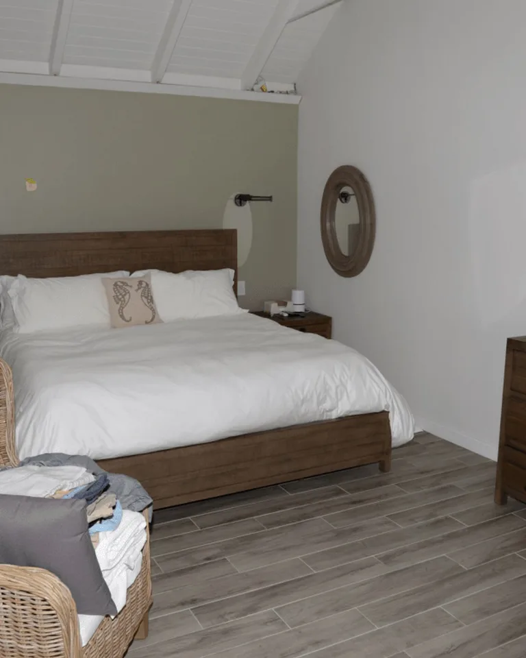A bedroom with a wooden bed frame and natural woven textures beside olive tones