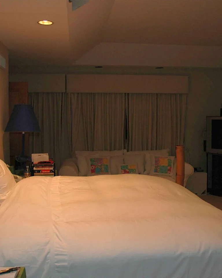 A moody dimly lit bedroom with olive walls and black metal accents