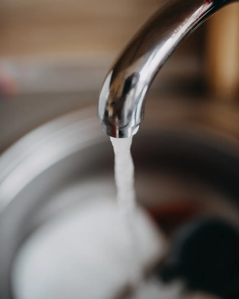 Water flowing from a modern kitchen faucet into the sink