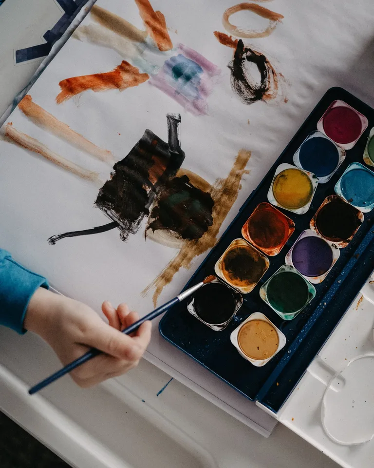 Watercolor paints and brush set out for a kids' art station