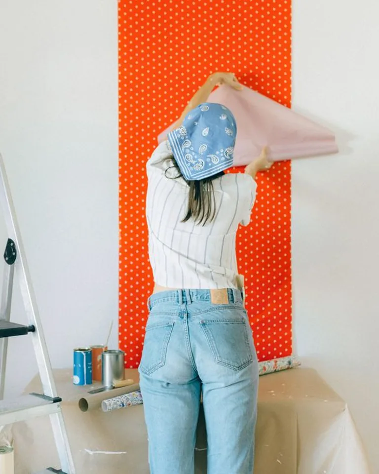 Person applying peel-and-stick wallpaper during a DIY room refresh