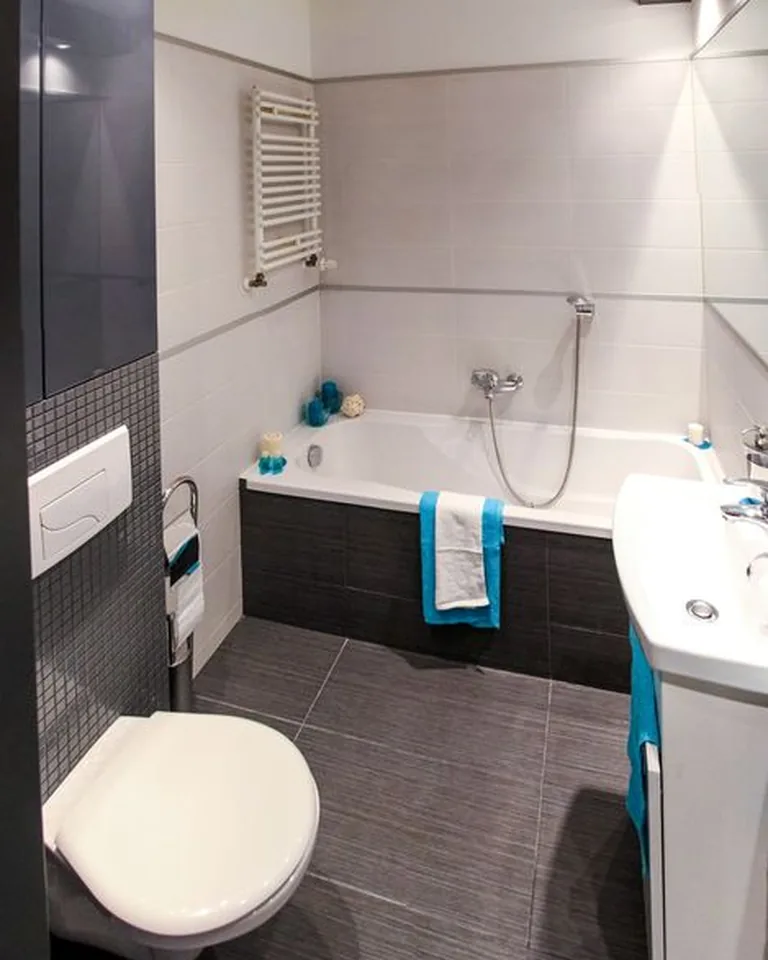 Finished rental bathroom makeover reveal with styled vanity, layered shower curtain, patterned rug, and warm lighting