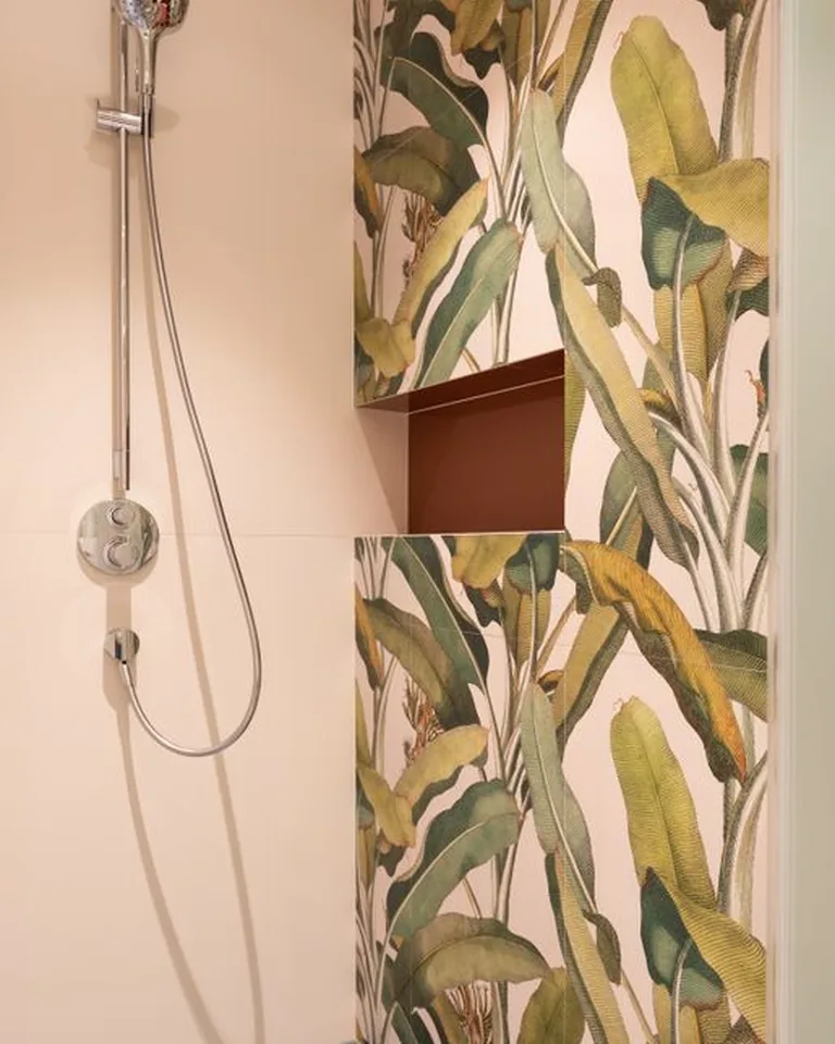 Rental bathroom with a botanical removable wallpaper accent wall behind a white bathtub