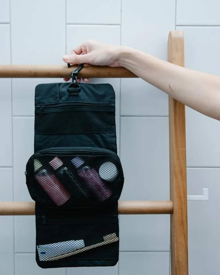 Hanging toiletry organizer on a wooden rack in a tiled bathroom, no-drill shower storage