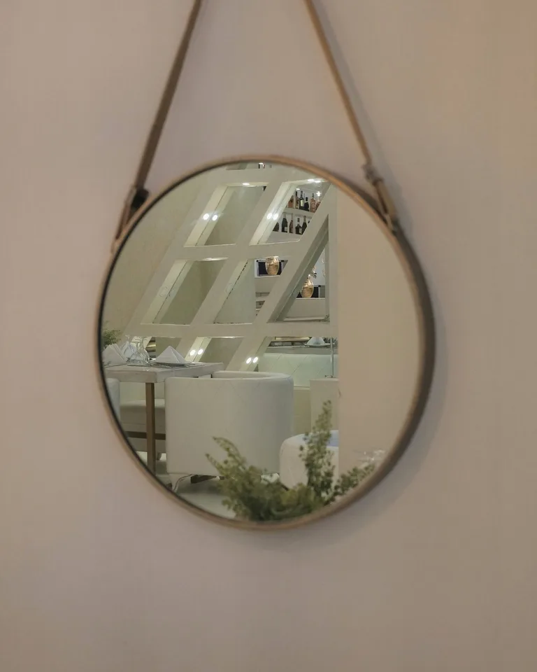 Round mirror with a warm bronze frame hanging on a white wall