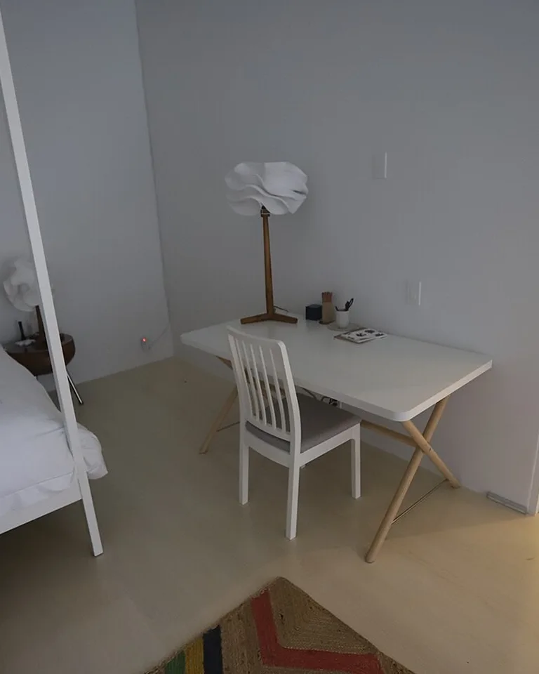 Simple bedroom corner lit by a wood-stem table lamp
