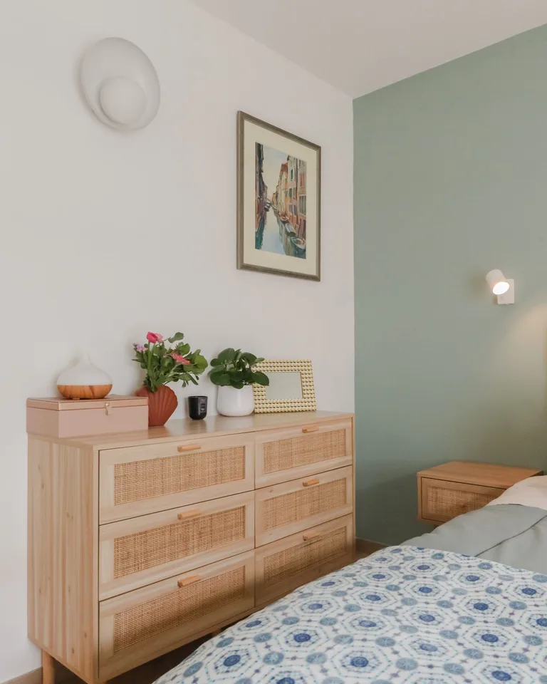 Light wood dresser with woven drawer fronts and wooden pulls in a sage green bedroom