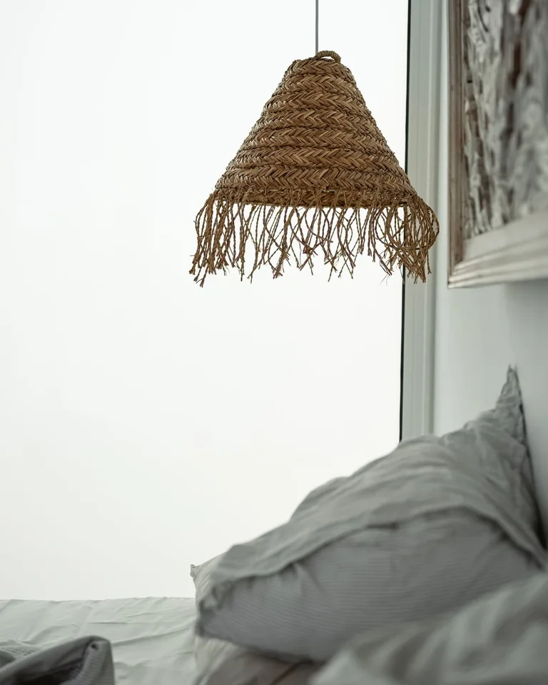 Woven rattan pendant shade hanging above a bed