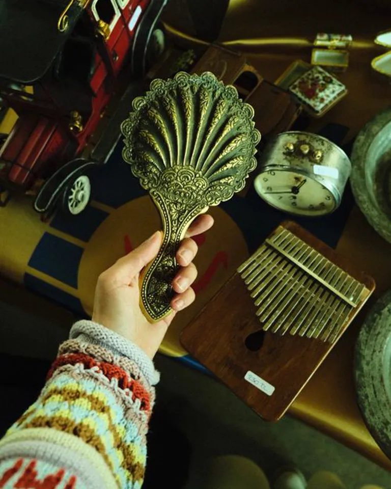 An ornate vintage hand mirror held among antique finds