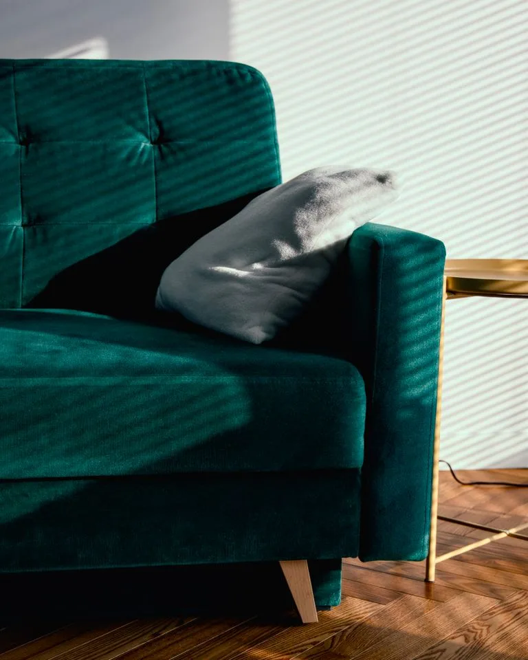Green velvet sofa anchoring a small neutral living room