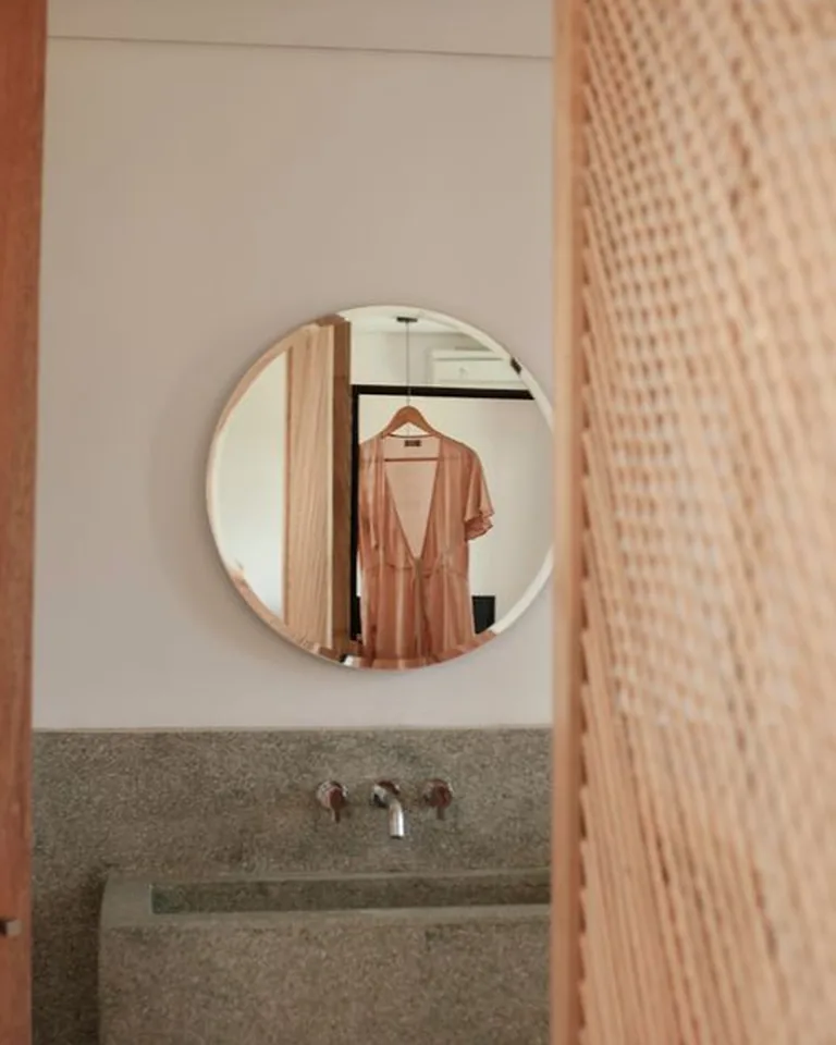 Large round mirror mounted above a small bathroom sink