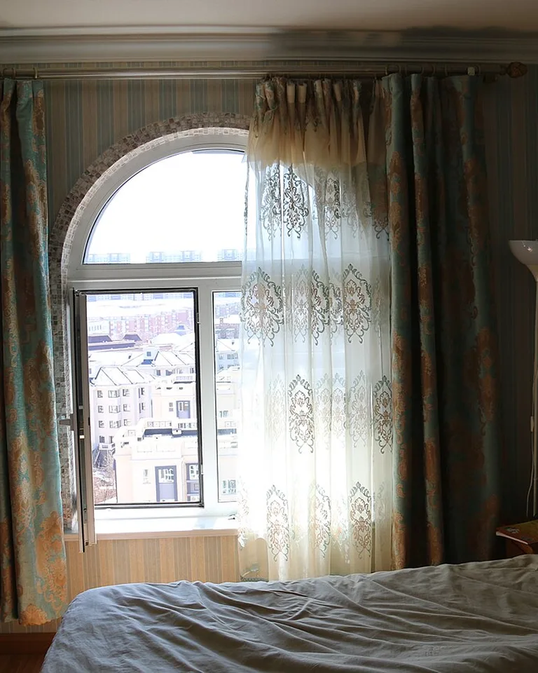 Long curtains mounted near the ceiling in a bedroom