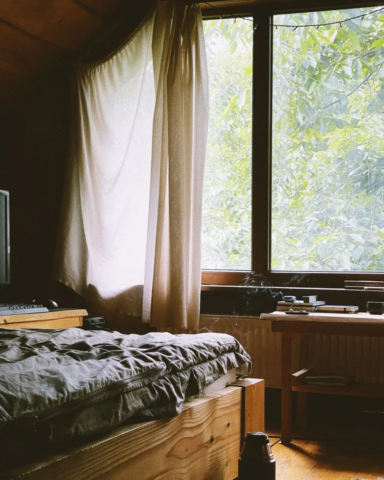 Small bedroom filled with natural window light and simple furnishings