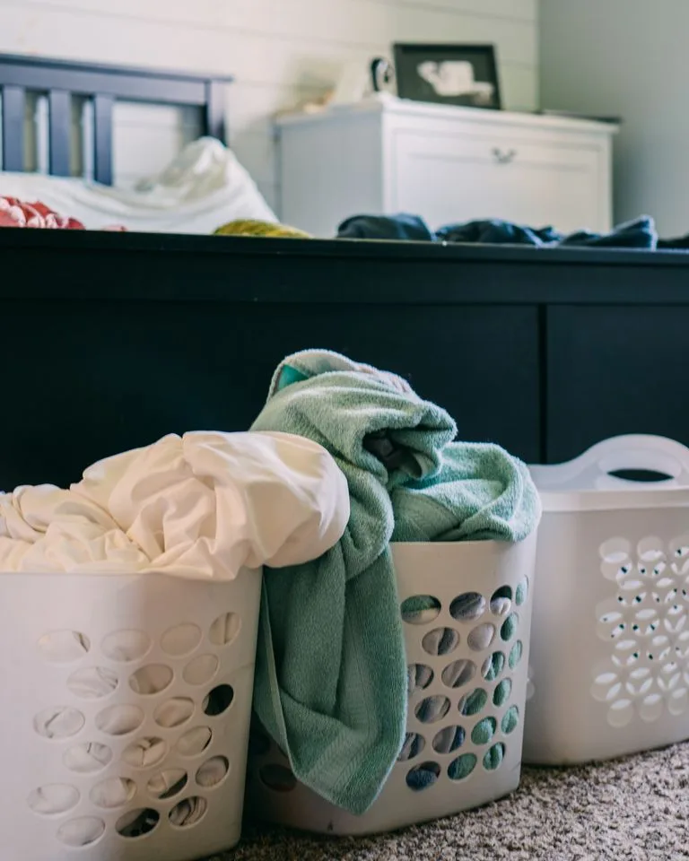 Woven storage baskets standing on the floor beside a bed