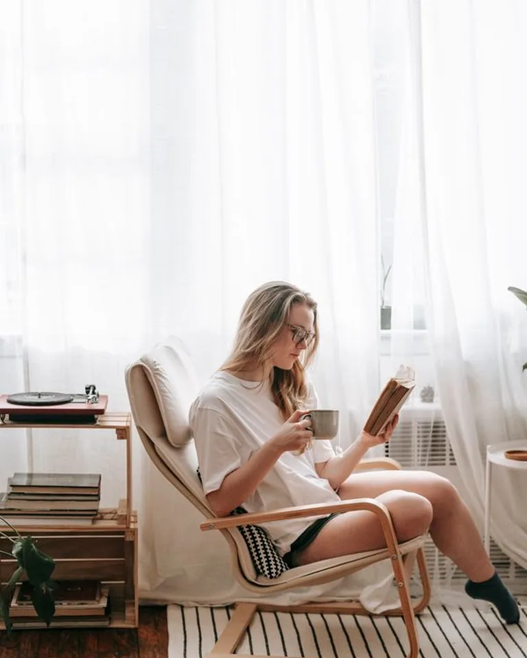 A woman reading in a cozy chair by a bright window