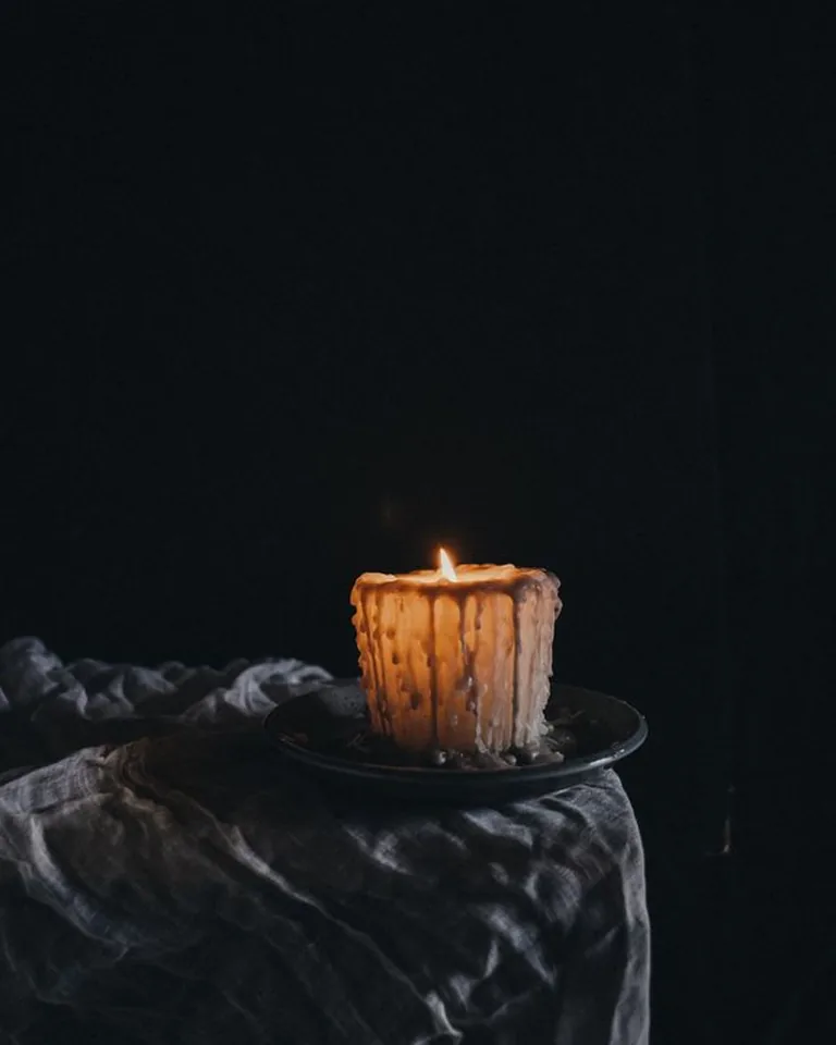 A lit candle glowing in a dark, cozy room
